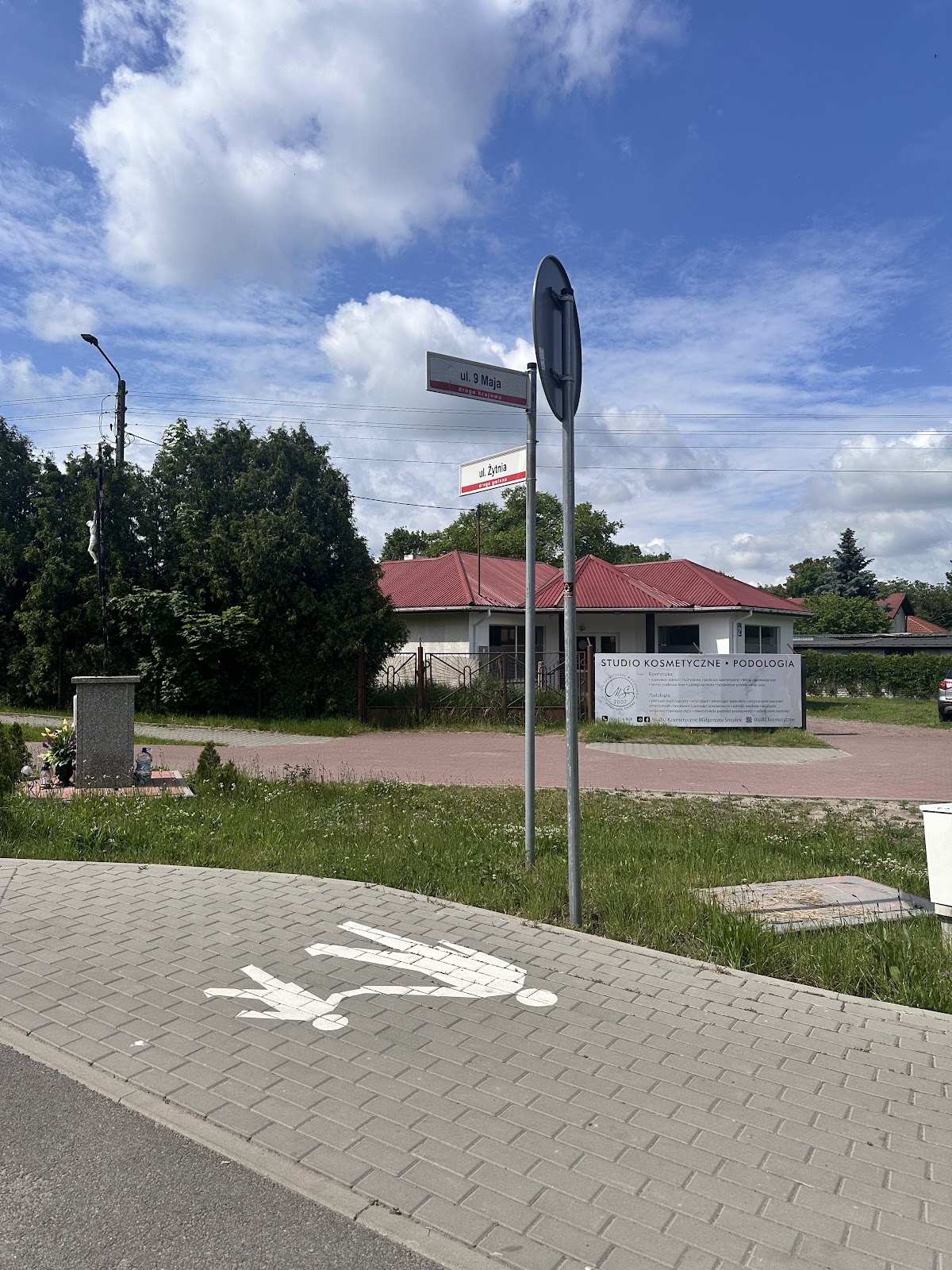 Widok na gabinet od strony ul. 9 Maja · znaki drogowe, banner Studio Kosmetyczne Podologia widoczny z chodnika.